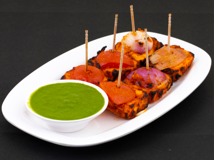 A colorful assortment of food on a plate, showcasing paneer tikka from Jheel Indian restaurant.